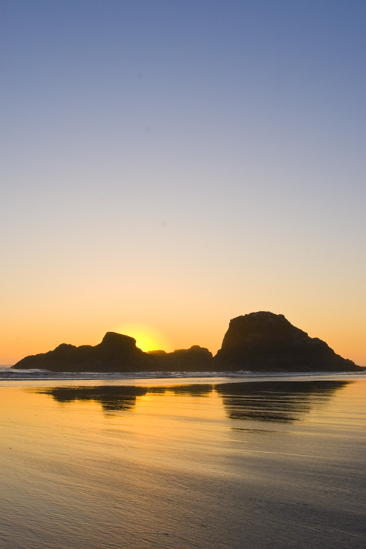 Seastack Silhouettes Reflected In Wet Sand At Sunset